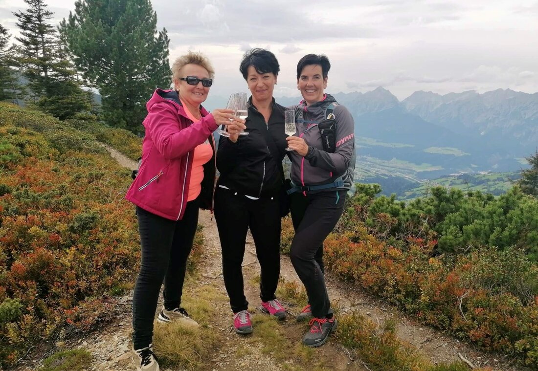 Drei Wanderer posieren für ein Foto mit einem Glas Sekt in der Hand
