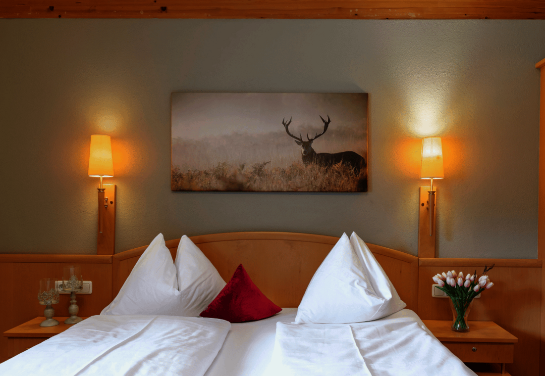 Doppelbett mit Nachttisch und Hirschbild