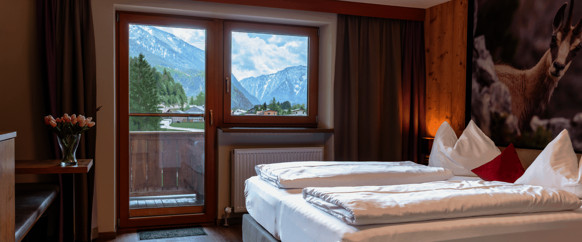 Doppelbett mit Sitzgelegenheit und Blick zum Balkon