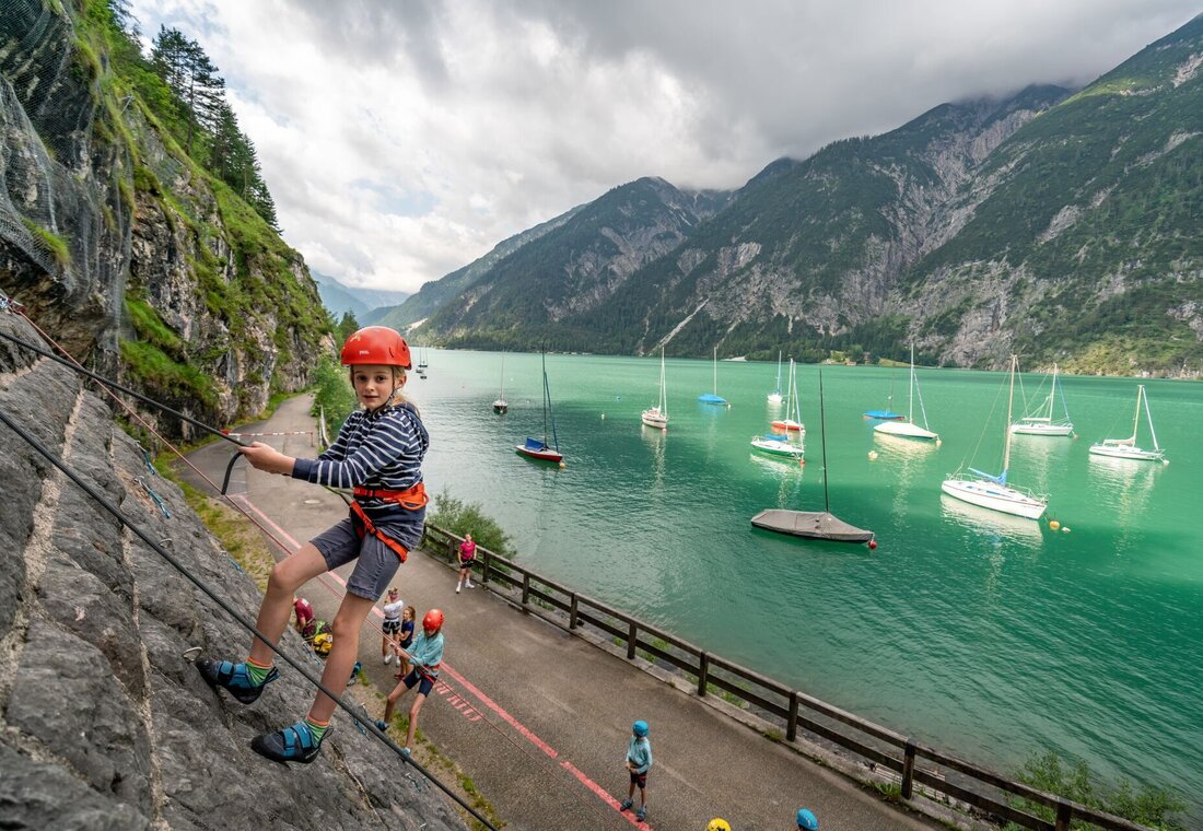 Kinder klettern auf einer Felswand neben dem See