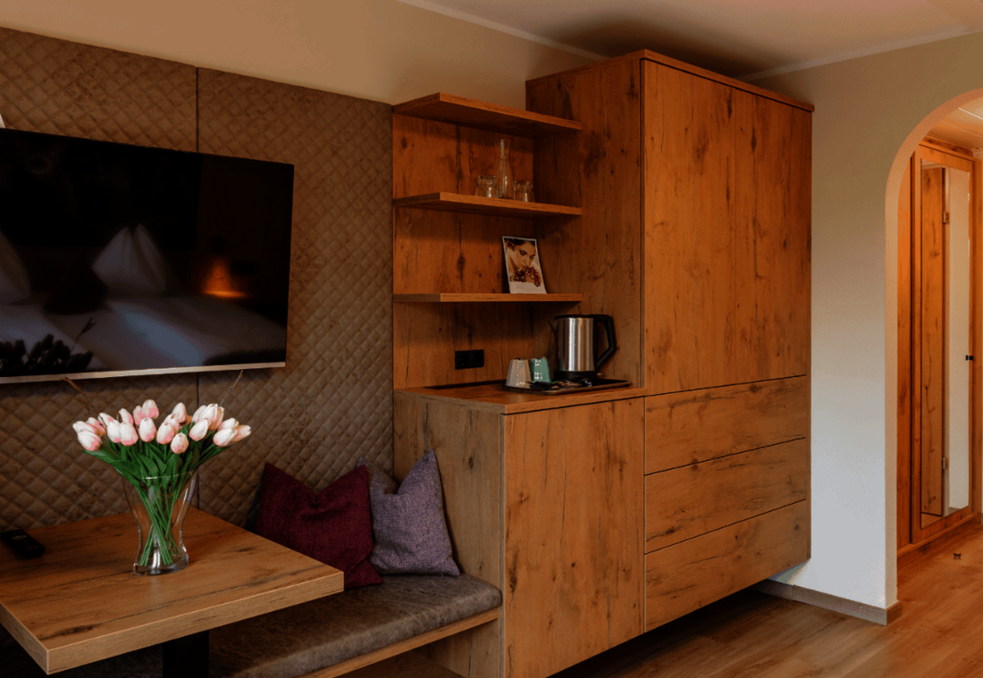 Seating area in the double room with a table, TV, kettle and natural wood furniture