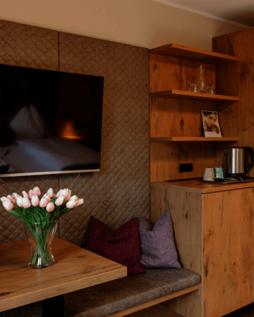 Sitzbereich im Doppelzimmer mit Tisch, TV, Wasserkocher und Naturholzmöbeln