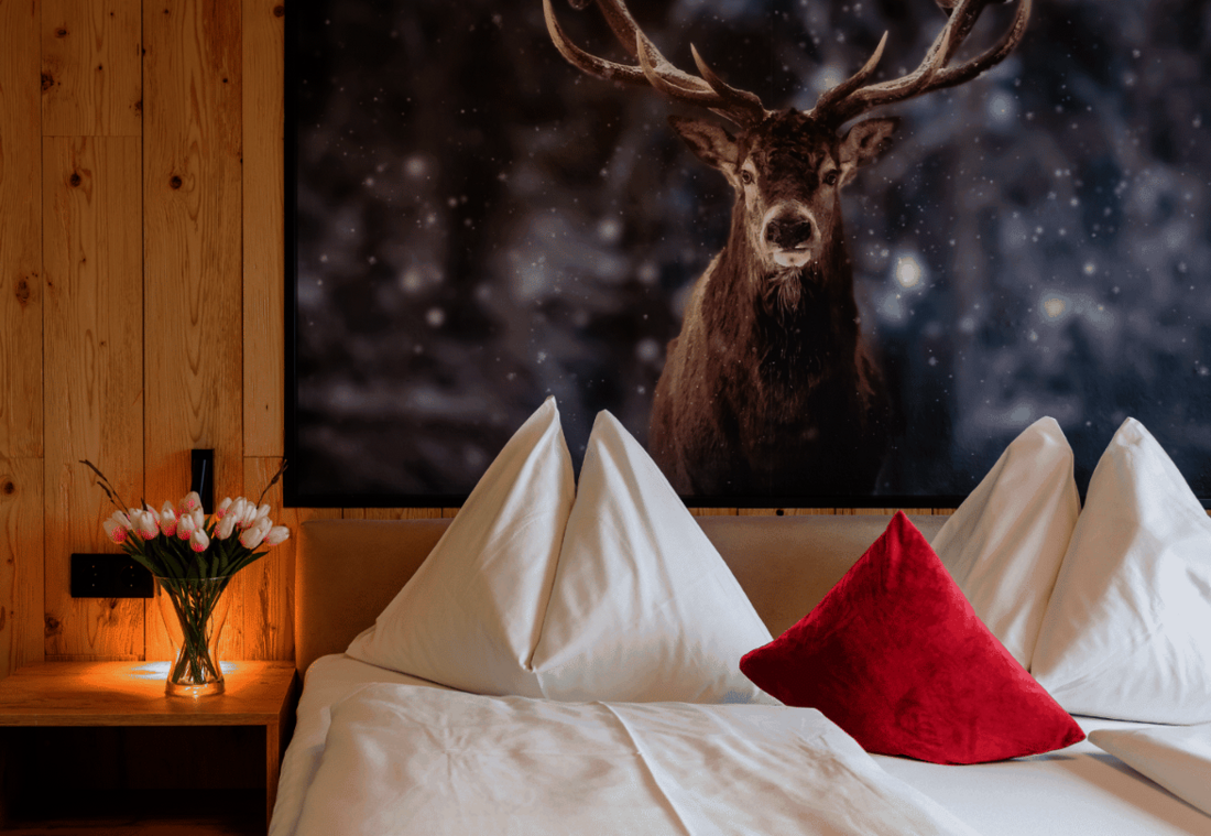 Double bed with white pillows, natural wood and a large stag motif