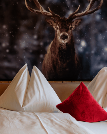 Doppelbett mit weißen Kissen, Naturholz und großem Hirschmotiv