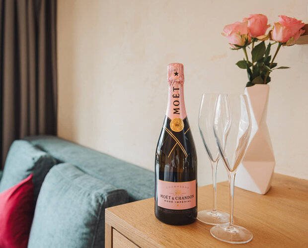 Flasche Sekt mit Strauß Rosen und Couch
