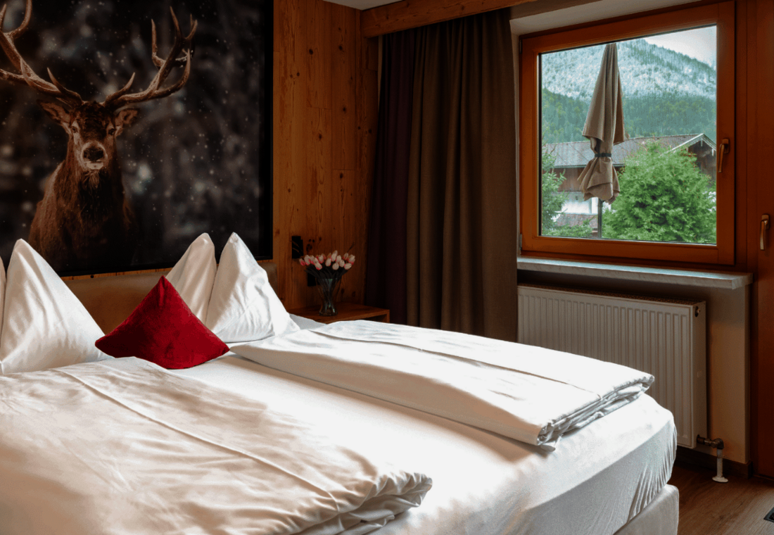 Doppelzimmer mit Hirschmotiv, großem Fenster und Zugang zum Balkon