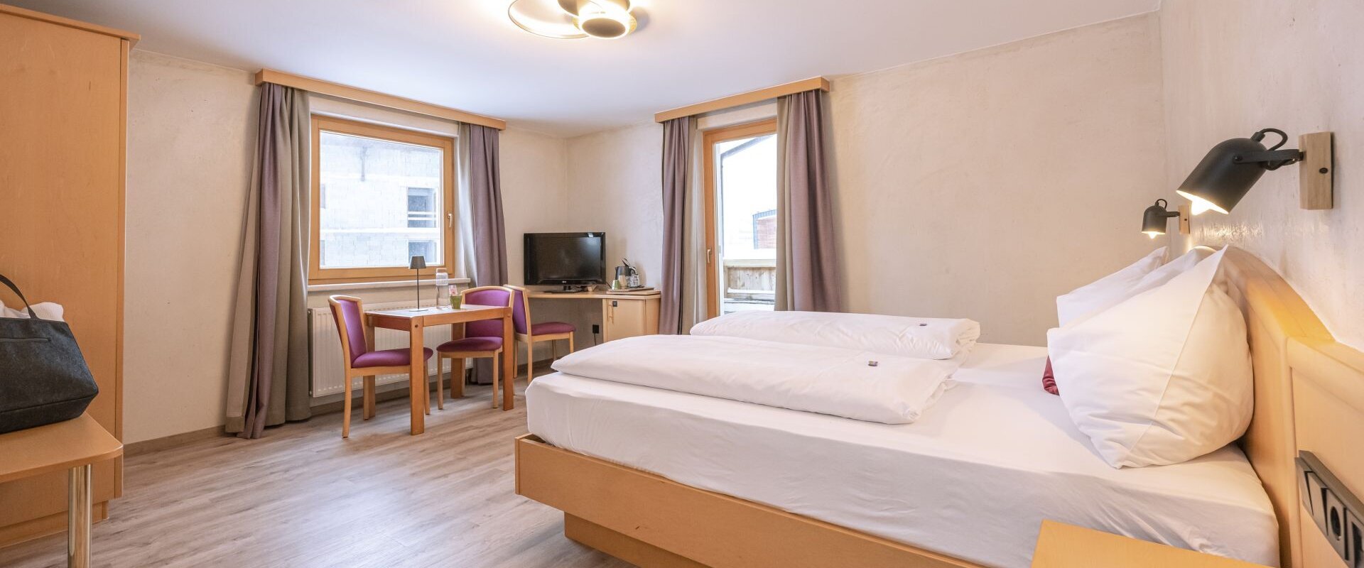 Hotelzimmer mit Bett, Tisch, Stühlen und einem Fernseher