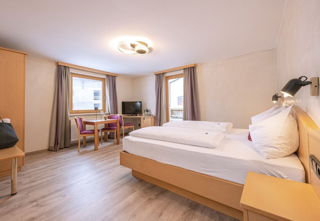 Hotelzimmer mit Bett, Tisch, Stühlen und einem Fernseher