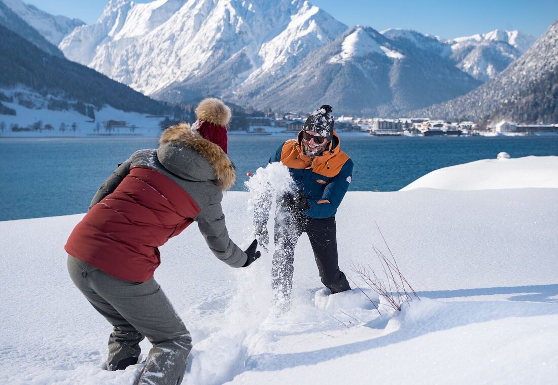 Paar spielt im Schnee am Ufer des Achensees