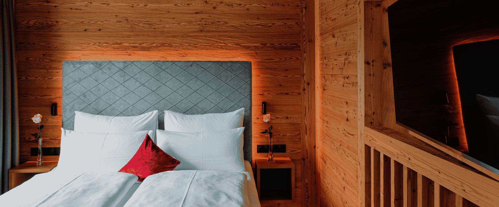 Doppelbett mit offenem Dachstuhl und TV an der Wand