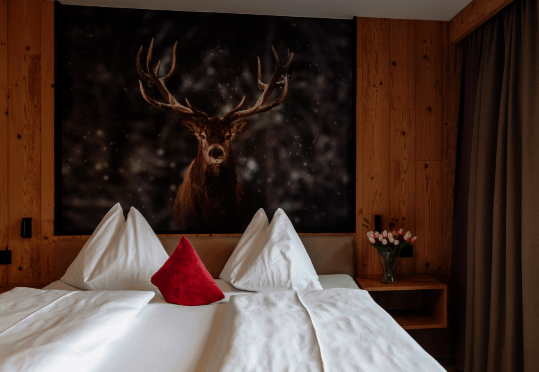 Cosy double room with natural wood panelling and a stag motif above the bed