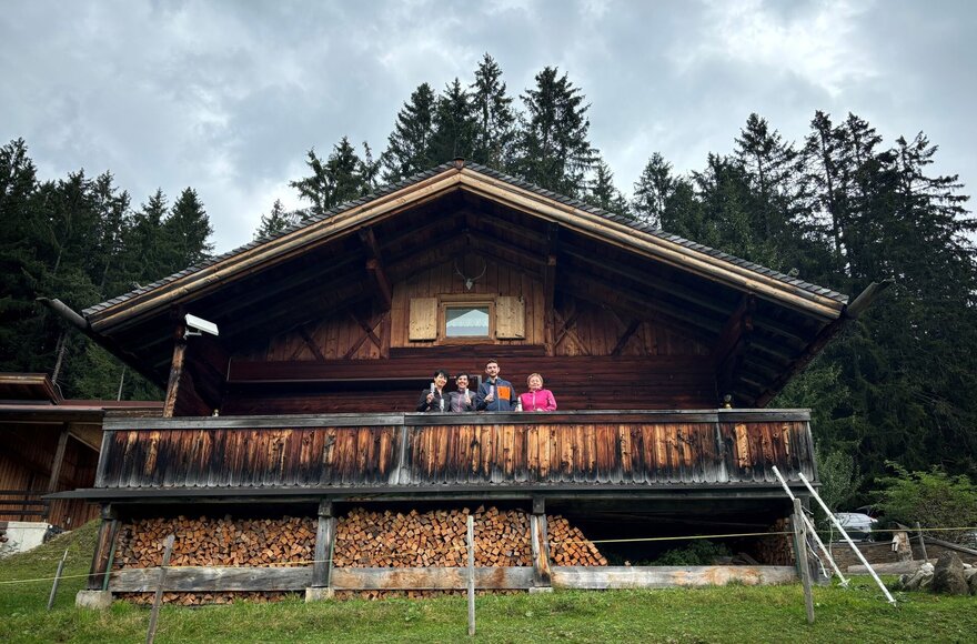Vier Menschen vor einer Hütte am Waldrand