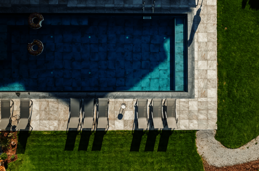 Drohnenaufnahme vom Pool mit Sonnenliegen und Schwimmreifen
