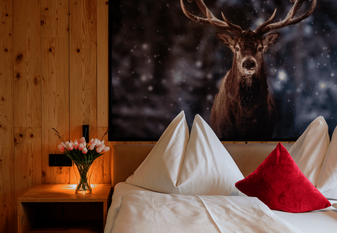 Bett mit Nachtisch und Hirschbild 