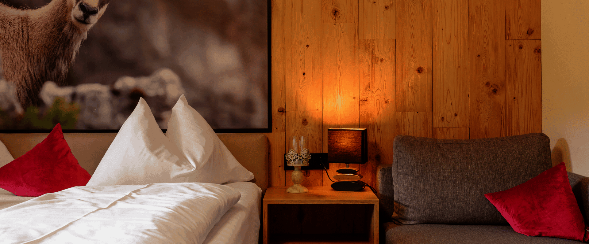 Doppelbett mit Gamsbild und Couch im Doppelzimmer
