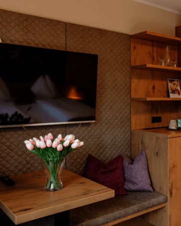 Sitzgelegenheit mit Blumen am Tisch und TV an der Wand