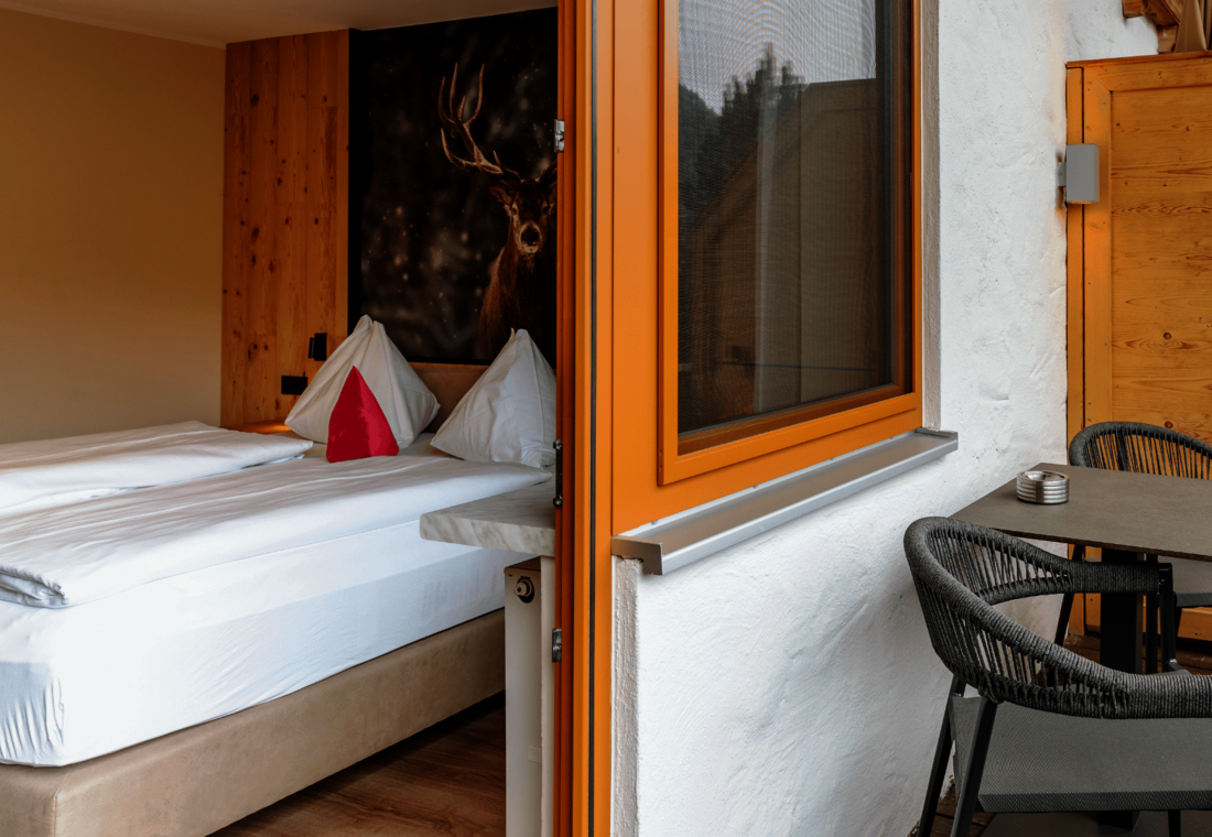 Doppelbett mit Hirschbild und Einblick auf den Balkon