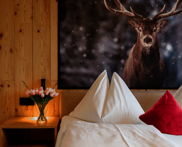 Gemütliches Doppelbett mit Naturholz und großem Hirschbild