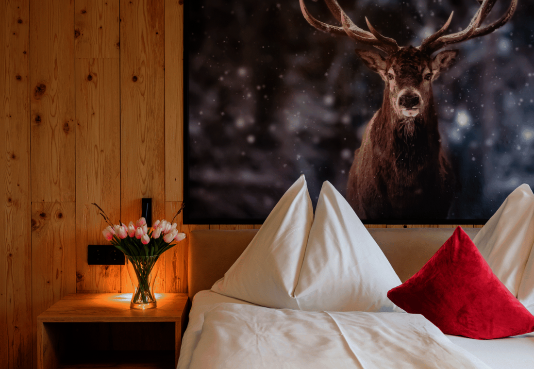 Gemütliches Doppelbett mit Naturholz und großem Hirschbild