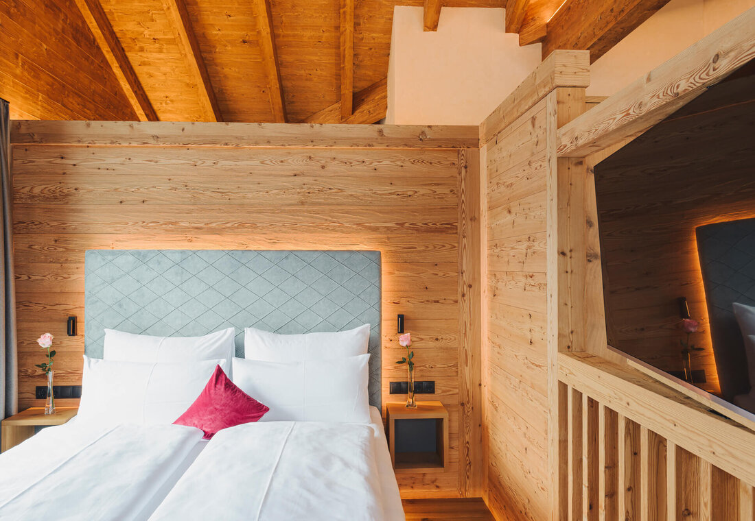 Doppelbett mit TV an der Wand und großem Dachstuhl